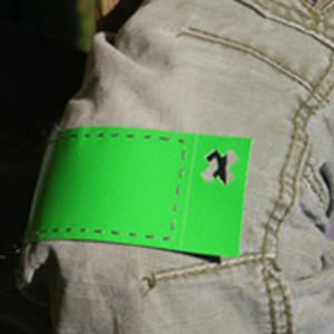 May include: A bright green fabric patch with a small, rectangular hole in the center. The patch is sewn onto a pair of brown jeans.
