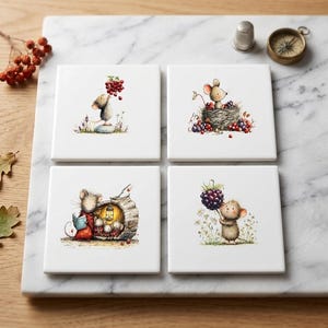 Puede incluir: Un juego de cuatro posavasos cuadrados de cerámica blanca con ilustraciones de ratones estilo acuarela. Los diseños muestran un ratón con bayas rojas, uno en un nido, ratones en un tronco y uno sosteniendo una mora. Acabado liso.
