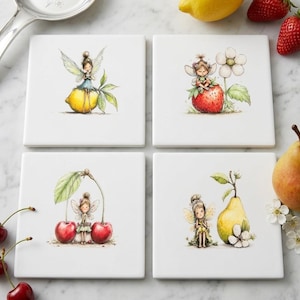 Puede incluir: Un juego de cuatro posavasos cuadrados de cerámica blanca con ilustraciones en acuarela de pequeñas hadas. Cada posavasos muestra a un hada interactuando con una fruta diferente: un limón, una fresa, un par de cerezas y una pera.