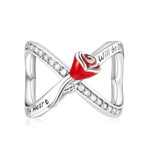 Puede incluir: Anillo plateado con un diseño de símbolo de infinito. El anillo presenta una rosa roja en el centro y está adornado con pequeñas piedras preciosas transparentes. Las palabras "My Heart" y "Will Go On" están inscritas en el anillo.