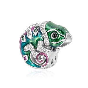Può includere: Un ciondolo in argento a forma di camaleonte arrotolato, caratterizzato da smalto verde, blu e viola con una finitura glitterata. Il camaleonte è impreziosito da piccole pietre chiare sul dorso e sulle zampe e ha un unico occhio nero.