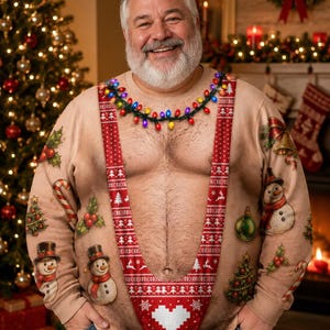 Op de afbeelding: Een beige sweater met lange mouwen en ronde hals, voorzien van een realistische print van een blote borstkas met een rood-wit patroon in bretelstijl, een snoer met gekleurde kerstverlichting rond de hals en feestelijke kerstmotieven.