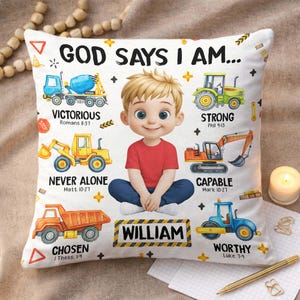 Peut inclure: Coussin blanc décoratif avec une illustration de garçon en chemise rouge et pantalon bleu. Le coussin porte l'inscription "GOD SAYS I AM..." et des mots inspirants avec des versets bibliques, ainsi que le nom "WILLIAM".