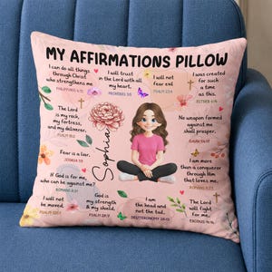 May include: A square throw pillow with a light pink background featuring the text MY AFFIRMATIONS PILLOW, a central illustration of a girl with brown hair wearing a pink shirt, and various religious quotes with floral and butterfly accents.