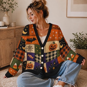 Peut inclure: Un cardigan à manches longues et col en V avec un motif patchwork de graphismes sur le thème d'Halloween, incluant des citrouilles, chauves-souris, toiles d'araignée, bonbons et une maison hantée en orange, noir, vert et violet, avec boutons blancs.