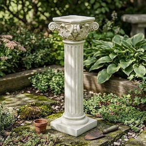 Puede incluir: Un pedestal de jardín de color blanco roto, con una columna cilíndrica estriada y una base cuadrada. La parte superior del pedestal está adornada con detalles tallados de hojas y volutas en un estilo arquitectónico clásico.