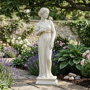 Puede incluir: Estatua clásica de piedra blanca de una mujer con un vestido fluido, con un pájaro posado en su hombro. La estatua se alza sobre una base cuadrada, en un jardín con exuberante vegetación y flores. La estatua mide unos 152 cm de altura.