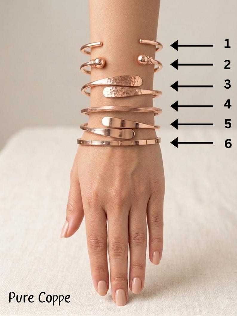 May include: Six copper cuff bracelets arranged in a vertical stack, numbered one through six with black arrows. The designs include plain bands, ball-end terminals, hammered textures, and smooth flat-end styles. The text Pure Coppe is visible.