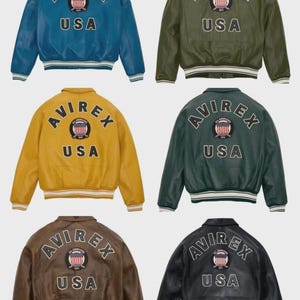 May include: Six leather bomber jackets in various colors: blue, olive green, yellow, dark green, brown, and black. Each jacket features the "AVIREX" logo and "USA" text on the back, with a striped hem and cuffs.