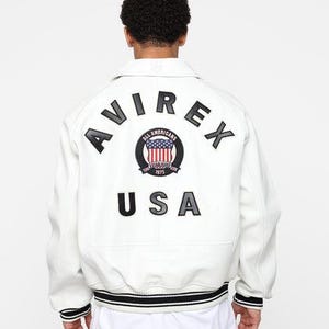 May include: White jacket with black and white striped trim and the text "AVIREX USA" on the back. The jacket features a circular patch with a US flag design and the words "ALL AMERICANS 1975".