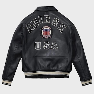 May include: Black leather jacket with the word "AVIREX" arched across the back in white lettering. Below the word "AVIREX" is a circular patch with the words "ALL AMERICANS ESTABLISHED 1975" and a US flag design. The word "USA" is below the patch.