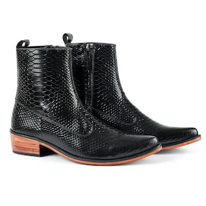 May include: A pair of black ankle boots featuring a textured snakeskin pattern, a side zipper closure, a pull tab at the heel, and a stacked wooden heel with a natural light brown finish and a thin orange layer along the sole edge.