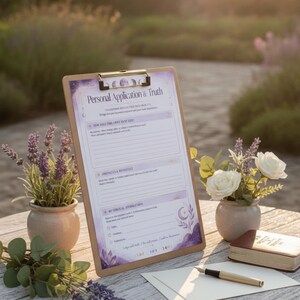 Puede incluir: Un portapapeles de madera con una hoja impresa titulada Personal Application & Truth con secciones para reflexión, obstáculos y afirmaciones. El papel presenta detalles en acuarela morada, fases lunares e ilustraciones florales, acompañado de una pluma estilográfica.