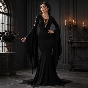 Peut inclure: Une robe noire longue jusqu'au sol avec de longues manches évasées, un décolleté en V profond doté d'un laçage style corset et des détails lacés sur le haut des bras. Le vêtement présente un corsage ajusté et une jupe évasée style sirène.