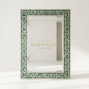 May include: Rectangular mirror with a green and white Greek key design border. The mirror has a silver frame and the text "HEARTH & HALO CREATION" in gold lettering.