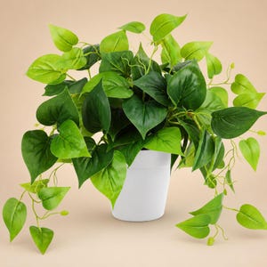 Puede incluir: Una planta artificial verde con hojas en forma de corazón en una maceta blanca. La planta tiene múltiples tallos y hojas en varios tonos de verde, creando una apariencia exuberante. La maceta tiene un diseño simple y moderno.