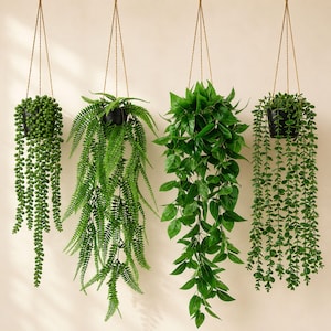 May include: Four hanging artificial plants in black pots suspended by brown twine. The plants display diverse green foliage, including trailing vines and fern-like leaves. The backdrop is a neutral, off-white hue.