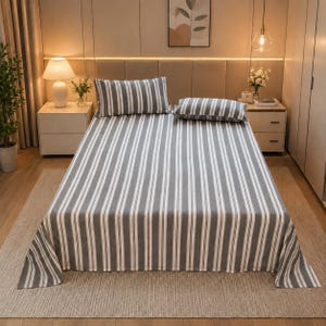 May include: A bed sheet set featuring a pattern of vertical grey and white stripes. The set includes a large flat sheet covering the mattress and two rectangular pillows, each matching the striped design of the bedding in a coordinated style.