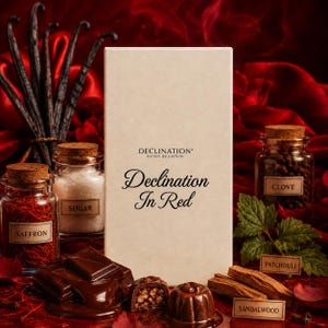 May include: A rectangular off-white box labeled Declination In Red extrait de parfum, surrounded by glass jars containing saffron, sugar, and clove, along with dark chocolate pieces, a patchouli leaf, and sandalwood sticks.