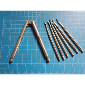 Pode incluir: Um quebra-nozes de metal prateado e cinco picaretas de nozes finas a condizer com cabos texturizados. O quebra-nozes mede cerca de 15 cm de comprimento e as picaretas medem cerca de 15 cm de comprimento, conforme a grelha.