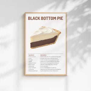 Peut inclure: Impression encadrée d'une part de Black Bottom Pie. La tarte a une base de chocolat noir, une garniture crémeuse à la crème anglaise et une garniture de crème fouettée. Le texte "BLACK BOTTOM PIE" est en haut.