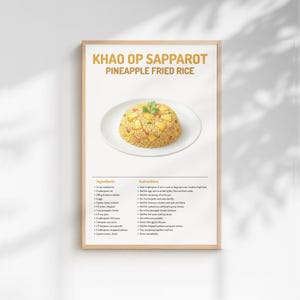 Puede incluir: Una impresión enmarcada con una receta de Khao Op Sapparot, o arroz frito con piña. El plato se presenta en un plato blanco. La receta incluye ingredientes e instrucciones. El texto está en inglés.