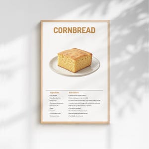 Peut inclure: Une affiche encadrée présentant une recette de pain de maïs. Le titre "CORNBREAD" est en lettres dorées. Une part carrée de pain de maïs doré est posée sur une assiette blanche. Ingrédients et instructions sont en dessous.