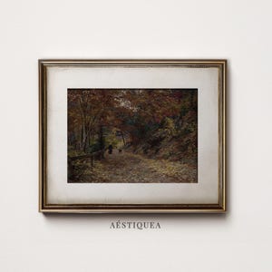 Puede incluir: Un cuadro de paisaje enmarcado que representa un camino cubierto de hojas de oto&ntilde;o ca&iacute;das que serpentea a trav&eacute;s de un bosque denso con &aacute;rboles y follaje oscuros. Una peque&ntilde;a figura camina por el sendero. La obra est&aacute; en un marco dorado met&aacute;lico con un paspart&uacute; ancho de color blanco roto. El texto A&Eacute;STIQUEA est&aacute; impreso debajo del marco.
