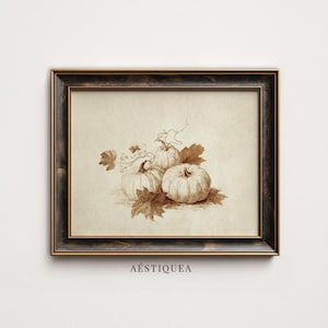 May include: A framed wall art piece featuring a sepia-toned sketch of three pumpkins with stems and leaves on a cream-colored background. The frame is dark brown with a textured finish. The text AÉSTIQUEA is printed in black below the frame.