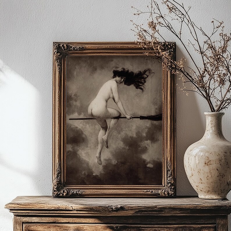 May include: A framed wall art print featuring a sepia-toned illustration of a figure with long dark hair riding a broomstick through a cloudy sky. The artwork is enclosed in an ornate, dark brown wooden frame with intricate carved detailing.