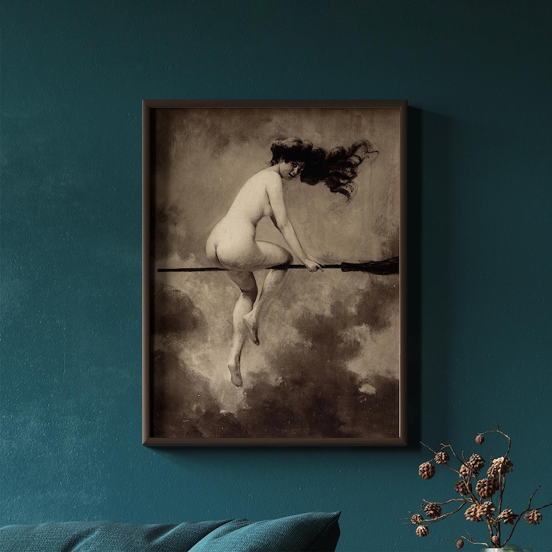 May include: A framed sepia-toned art print depicting a figure with long flowing hair riding a broomstick through a cloudy sky. The artwork features a monochromatic palette with dark brown and cream tones, presented in a simple dark brown frame.
