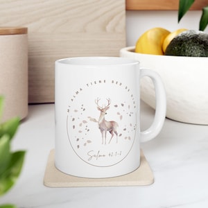 May include: White ceramic mug with a deer illustration and the text "MI ALMA TIENE SED DE DIOS" and "Salmo 42:1-2". The design features a deer with antlers and falling leaves in a circular arrangement.