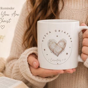 May include: White ceramic mug with a heart design and the text "Nueva Criatura" and "2 Corinthians 5:17". The mug also has the text "A Daily Reminder of Who You Are in Christ".