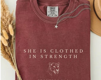 She Is Clothed In Strength T-Shirt, Lioness Christian Shirt, Proverbs 31:25 Bible Verse Tee, Faith Shirt for Women, Multiple Colors