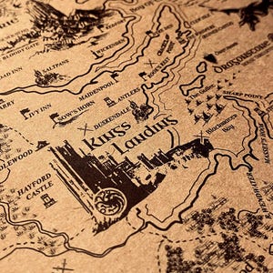 Puede incluir: Un mapa de pergamino de color tostado con ilustraciones en tinta negra de puntos de referencia geográficos, castillos y terreno. El mapa muestra etiquetas como King's Landing, The Eyrie, God's Eye y Kingswood, junto a una silueta de dragón.