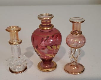 Set di 3 flaconi di profumo decorativi in vetro con finiture dorate e design floreale.