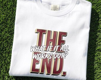 May include: A white short-sleeved t-shirt featuring a graphic print with the text THE WHAT IF IT ALL WORKS OUT? END. The letters are in a maroon colour with a cream-coloured 3D shadow effect, and the text is centred on the front of the garment.