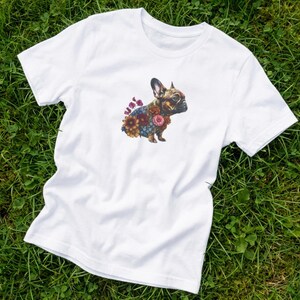 May include: White t-shirt with a watercolour illustration of a French Bulldog decorated with colourful flowers. The dog is shown in profile, highlighting its unique features. The design is centrally placed on the shirt, creating a visually appealing graphic.