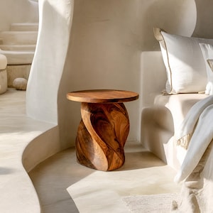 Puede incluir: Una mesa auxiliar de madera con tapa redonda y base retorcida. Hecha de madera marrón oscura, mostrando la veta natural. Una pieza decorativa elegante para salón o dormitorio. Altura aproximada de 50 cm.