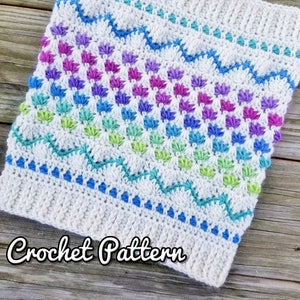 May include: A crochet pattern for a colorful cowl with a white background and a wavy blue, green, and purple design. The text "Crochet Pattern" is written below the cowl.