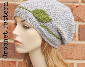 May include: Gray crochet beanie with a green leaf design. The beanie is slouchy and has a wide brim.
