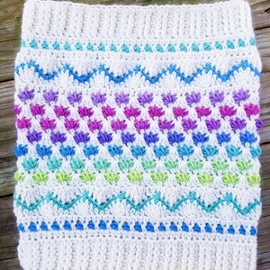 May include: White crochet headband with a colorful chevron pattern and a row of small flower-like stitches in shades of purple, blue, green, and white.