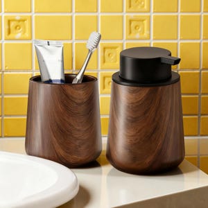 May include: A wooden bathroom set featuring a toothbrush holder with a tube of toothpaste and a toothbrush, and a soap dispenser with a black pump. The set has a dark wood grain pattern and is set against a yellow tile background.