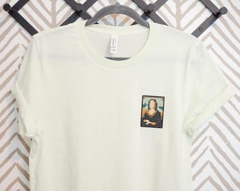 Cross Stitch Mona Lisa T-Shirt – Embroidered Pocket Art Tee, Funny Art Shirt, Minimalist Unisex Tee for Museum Lovers