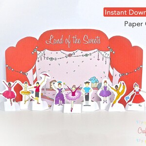 May include: A paper craft scene featuring a stage with the text "Land of the Sweets" and several paper figures of dancers. The stage is red and pink with a candy garland. The words "Instant Download" and "Paper Craft" are in the top right corner.