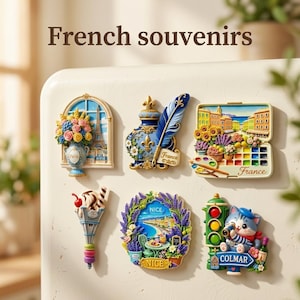 May include: Six decorative refrigerator magnets featuring French themes. Designs include a Paris window with flowers, an inkwell with a quill, a painter's palette, an Eiffel Tower ice cream cone, a Nice coastal scene, and a cat in Colmar.