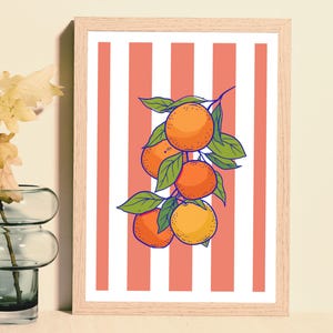 May include: A framed art print featuring a vibrant illustration of oranges on a branch with green leaves. The background has a striped pattern of coral and white. The frame is made of light-coloured wood.