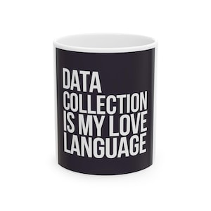 Op de afbeelding: Witte keramische mok met een zwarte band met de witte, vetgedrukte tekst "DATA COLLECTION IS MY LOVE LANGUAGE". De mok heeft een witte binnenkant en een standaard handvat.