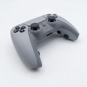 May include: A gray wireless game controller with black joysticks and buttons. The controller has a directional pad, action buttons, and a PlayStation logo. The design is ergonomic and modern, suitable for gaming.