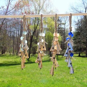 May include: A set of six wind chimes with different colored glass beads and star-shaped bells. The chimes are made of metal and have a rustic, natural look.